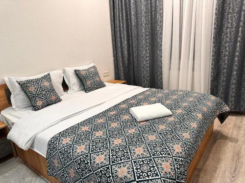 a bedroom with a bed with a blanket and pillows at Duet in Bishkek