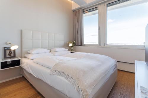a white bedroom with a large bed and a window at Skyline View Vienna - Gym - Parken - Supermarkt - Restaurant - Self Check in in Vienna