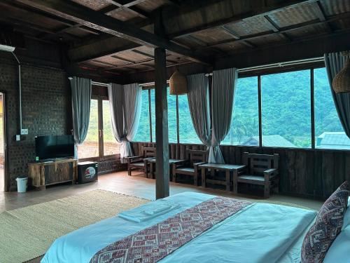 Un dormitorio con una cama y un televisor y ventanas. en HaGiang Go Ecolodge, en Làng Lap