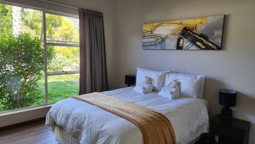 a bedroom with a bed with two teddy bears on it at The Hamlet House in Prince Alfreds Hamlet