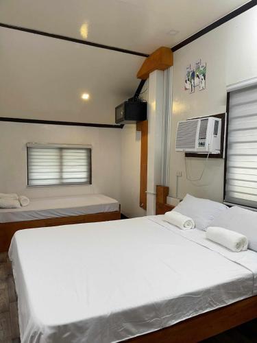 a bedroom with two beds and a air conditioner at Chia's Beach House Siargao in Cabalawan