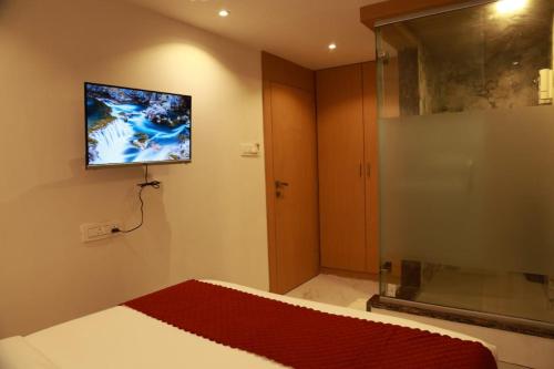 a bedroom with a bed and a tv on the wall at Hotel Stayzi Inn in Navi Mumbai