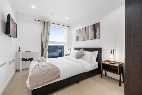 a bedroom with a large bed and a window at Panoramic City Views Elegant 2BR, 2 Min to Metro in Manchester
