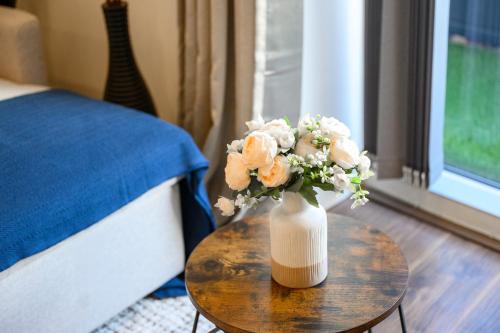a vase of flowers sitting on a table next to a bed at Panoramic City Views Elegant 2BR, 2 Min to Metro in Manchester