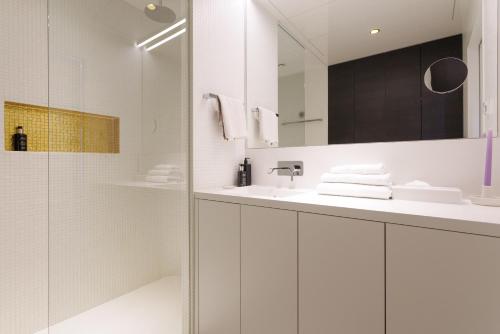 a white bathroom with a sink and a mirror at Skyline View - Gym - Parking - Supermarket - Restaurant - Self Ceck In in Vienna