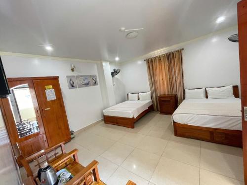 a hotel room with two beds and a table at Manh Vuong Hotel &Travel in Cat Ba