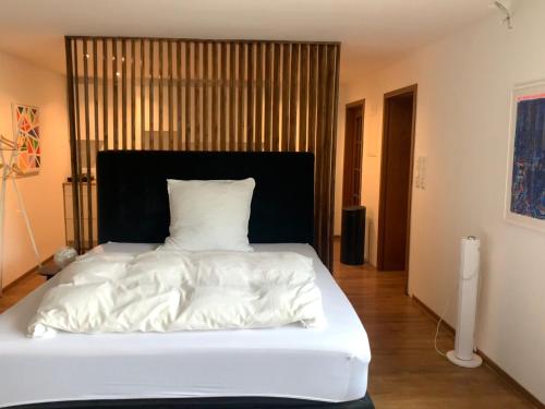 un letto bianco con testiera nera in una stanza di Messe Premium Apartment a Dusseldorf