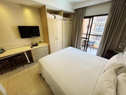 Una habitación de hotel con una cama, un escritorio y un televisor. en Destino Floripa Jurerê, en Florianópolis