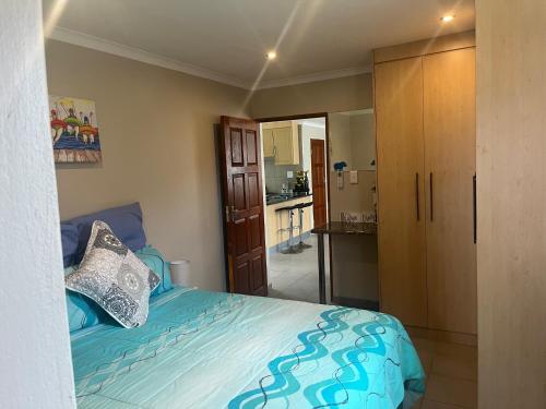 a bedroom with a blue bed and a kitchen at Imvubu Chalet in Sodwana Bay