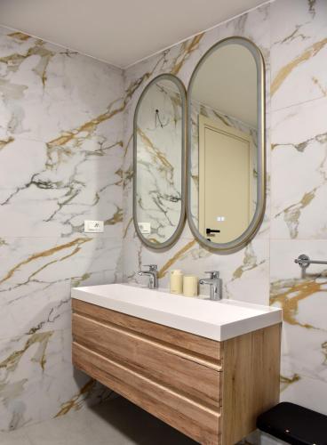 un bagno con un lavandino e due specchi di Apartments and Rooms Tomas a Podstrana