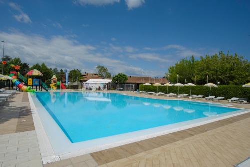 a large blue swimming pool with chairs and umbrellas at Ohana Apartments Camping Tiglio in Sirmione