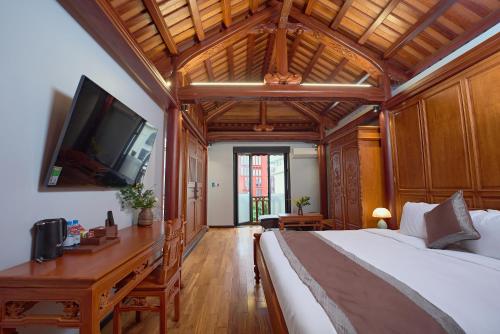 a bedroom with a large bed with a desk and a tv at Thong Dong Quán Boutique Hotel Hue in Hue