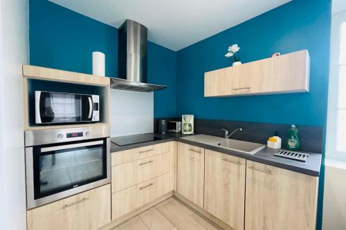 eine Küche mit blauen Wänden und Holzschränken in der Unterkunft Maison les mottes-cour et garage in Asnières-la-Giraud