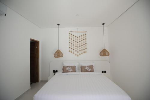 a bedroom with a white bed and two pendant lights at Villa Tamu 3 in Bingin Beach