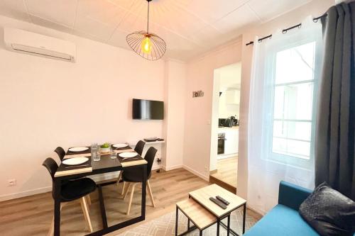 a dining room and living room with a table and chairs at Le Saintonge avec climatisation in Saintes