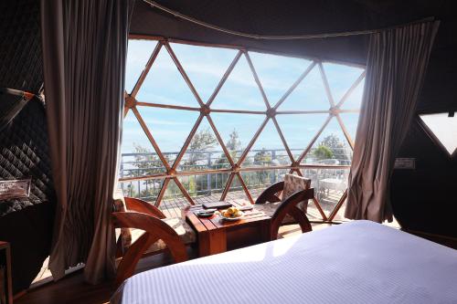 a bedroom with a large window with a table and chairs at ECKO Kasang Regency Hill Resort in Lansdowne