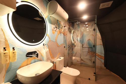 une salle de bain avec un lavabo et un miroir et des toilettes dans l'établissement ECKO Kasang Regency Hill Resort, à Lansdowne