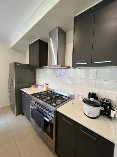 una cucina con mobili neri e un forno a piano cottura di My Home a Truganina