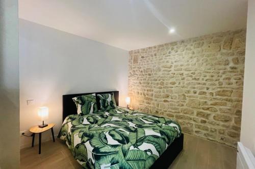 ein Schlafzimmer mit einem Bett und einer Steinwand in der Unterkunft Le Valentin in Saint-Jean-dʼAngély