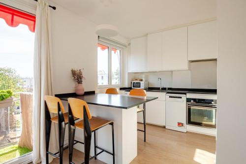 リュエイユ・マルメゾンにあるMaria’s placeの白いキャビネットとテーブルと椅子のあるキッチン