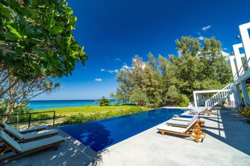 a swimming pool with lounge chairs and the ocean at Black Pearl 8 Bedroom Beach Villa Private Pool Gym Free Car Free Water and Electricity Maid 10 Meters to the Beach in Mai Khao Beach