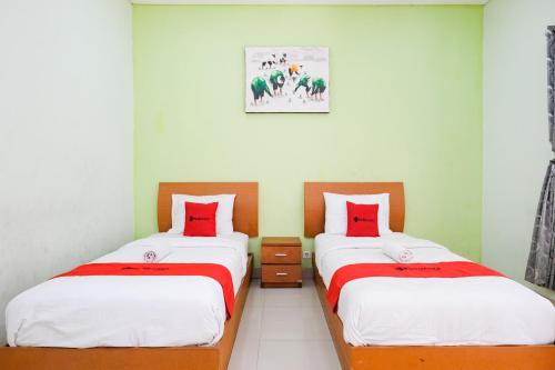 two beds sitting next to each other in a room at RedDoorz Plus @ Mahendradatta Denpasar in Denpasar