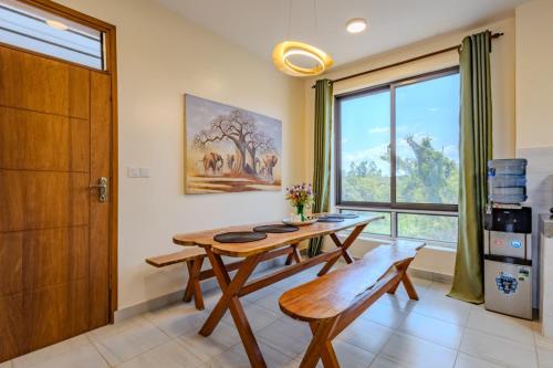 a dining room with a wooden table and a window at Casa Nampala Diani in Ukunda