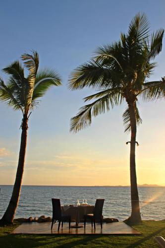 a table with chairs and palm trees on the beach at Radisson Blu Resort Fiji in Denarau