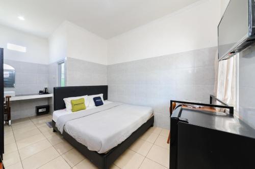 a bedroom with a bed and a bathroom with a sink at Urbanview Ava Guest House Goa Gong in Jimbaran