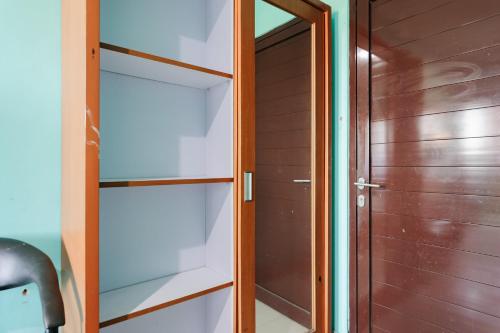 a closet with glass shelves next to a door at Gita Inn Bali RedPartner in Denpasar