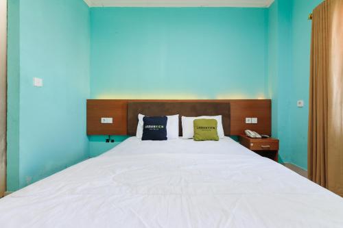 a bedroom with a large white bed with blue walls at Gita Inn Bali RedPartner in Denpasar