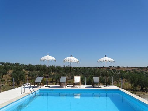 a swimming pool with chairs and umbrellas at Monte da Estrela - Country House & SPA in Moura