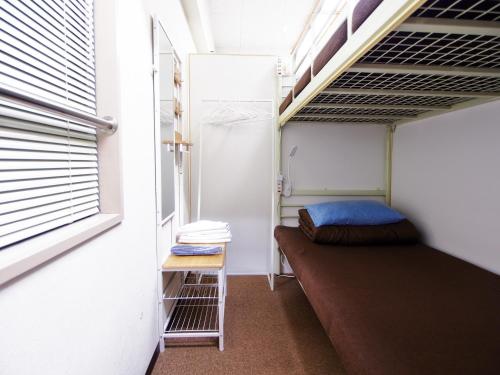 een kleine kamer met een stapelbed en een raam bij Omotenashi Hostel Miyajima in Hatsukaichi