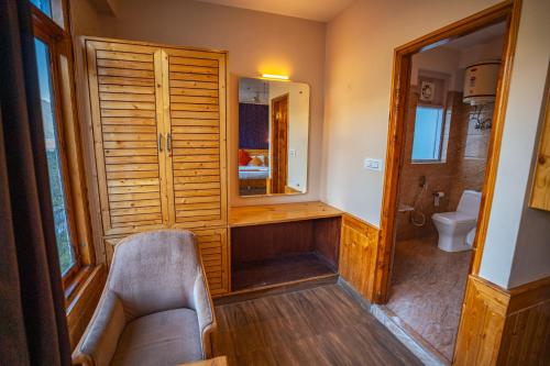 ein Badezimmer mit einem Stuhl und einem Spiegel in der Unterkunft The Northwood Cottages Manali, Mountain View with balcony, near mall road, manali in Manali