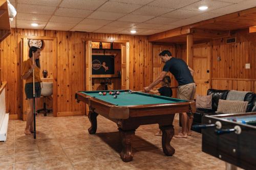 a man and woman playing pool in a room with a pool table at Chalet Alpin Walk to Lake and Beach with Spa and BBQ in Huberdeau