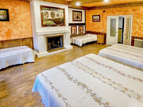 1 dormitorio con 2 camas y chimenea en Casa Viria, en Navaluenga