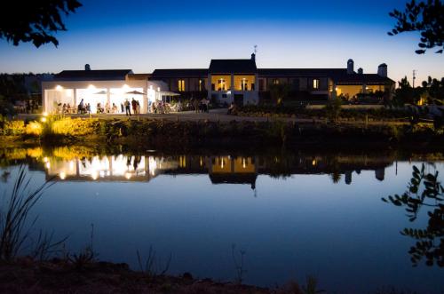 a lit up building next to a lake at night at Monte da Estrela - Country House & SPA in Moura