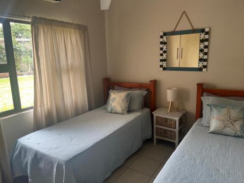 two beds in a room with a mirror and a window at Sibiya Guest House in Sodwana Bay