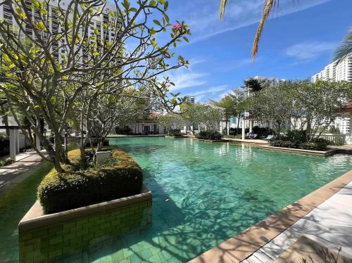 a swimming pool with a tree in the middle at Marina Chic l Stylish 2BR Retreat l Straits Quay in Tanjung Bungah