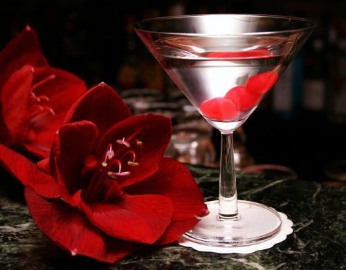 a martini glass with red hearts in it next to a red flower at De Keyser Hotel in Antwerp