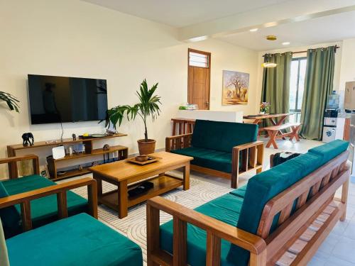 a living room with couches and a tv at Casa Nampala Diani 1 Bedroom Jungle in Diani Beach