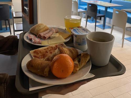 Una bandeja con dos platos de comida y una naranja encima. en Brit Hotel Le Polder, en Gravelines