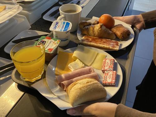 una mesa con dos platos de comida y un vaso de jugo de naranja en Brit Hotel Le Polder, en Gravelines