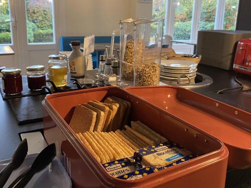Un recipiente naranja lleno de pan y galletas en un mostrador. en Brit Hotel Le Polder, en Gravelines