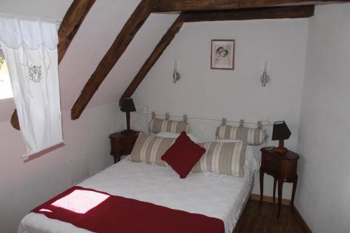 Schlafzimmer mit einem Bett mit weißer Bettwäsche und roten Kissen in der Unterkunft Les Vieilles Treilles in Noailhac