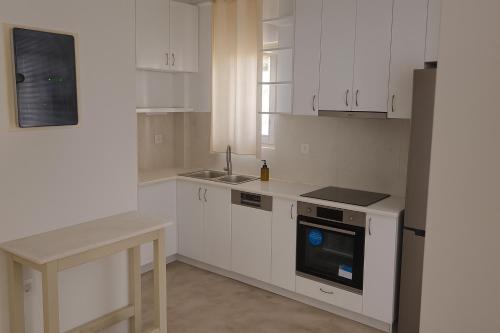 une cuisine blanche avec des armoires blanches et un évier dans l'établissement Persephone's Summer House Paros - 2BR Garden Villa, à Parasporos