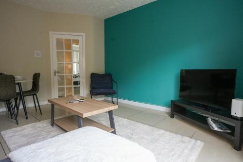a living room with a blue wall and a tv at Stobhill Apartment in Glasgow