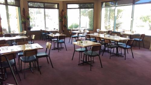 a dining room with tables and chairs and windows at Madison Spa Motel - Adults Only in Moama