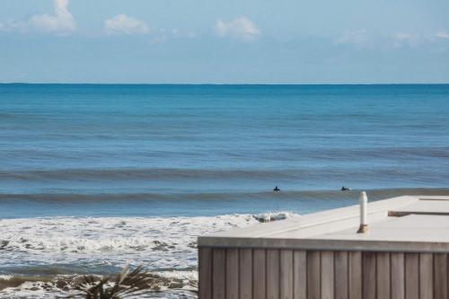 a view of the ocean with people in the water at Beach House On Hamblyn in New Plymouth