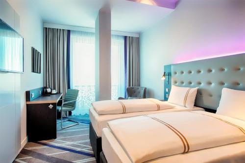 una habitación de hotel con dos camas y un escritorio en Premier Inn Lübeck City Stadtgraben, en Lübeck